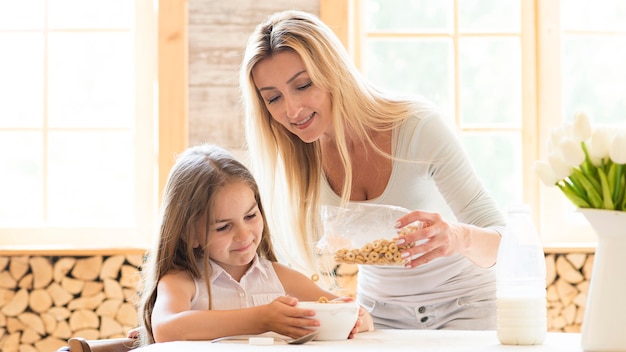 Free photo mother giving cereals for breakfast to daughter