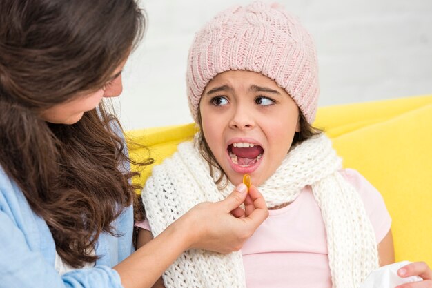 Mother giving her daughter a pill