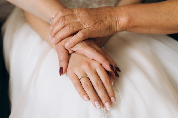 Free photo mother and grandma holds bride's hand