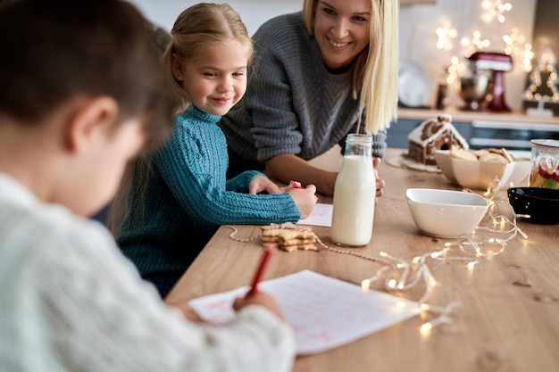 Mother helping children to write letter to Santa Claus