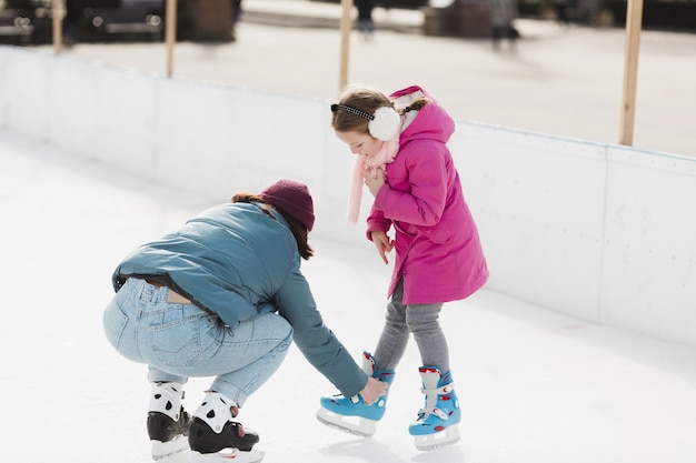 Mother helping cute daughter full shot