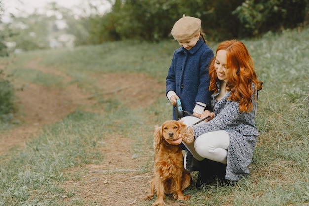 Free Photo mother and her daughter playing with dog. family in autumn park. pet, domestic animal and lifestyle concept. autumn time.