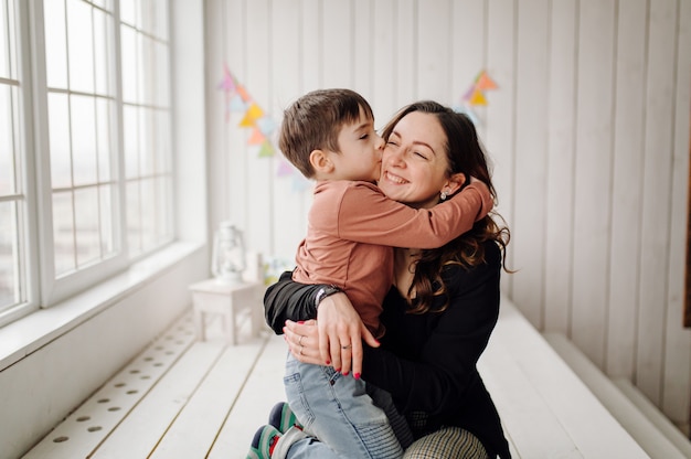 Mother and her son are posing in the studio and wearing casual clothes