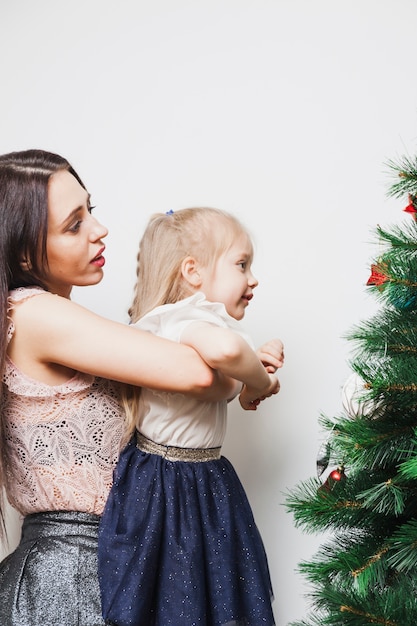 Mother holding daughter in front of christmas tree