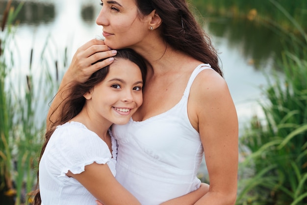 Free photo mother hugging daughter by the lake