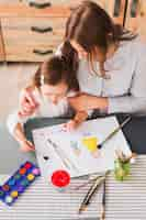 Free photo mother hugging daughter while she painting