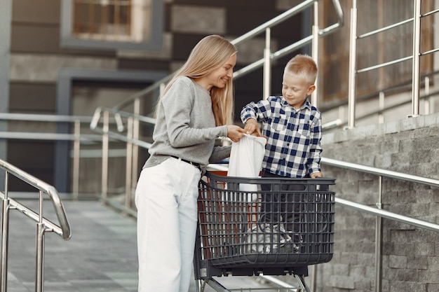 Mother is driving in a trolley. Family in a parking near a supermarket.