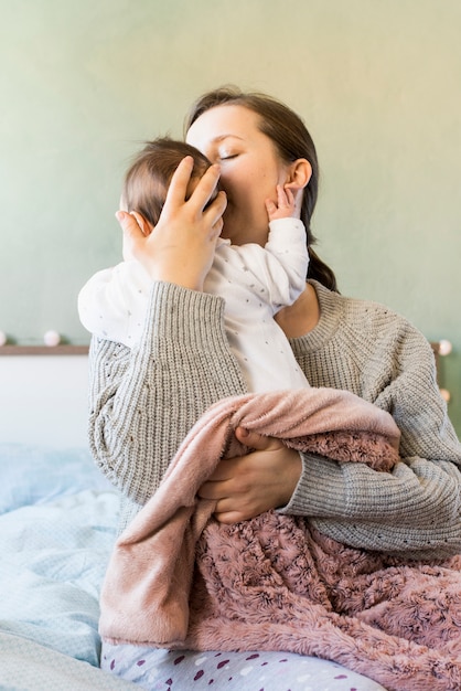 Free Photo mother kissing cute baby in arms