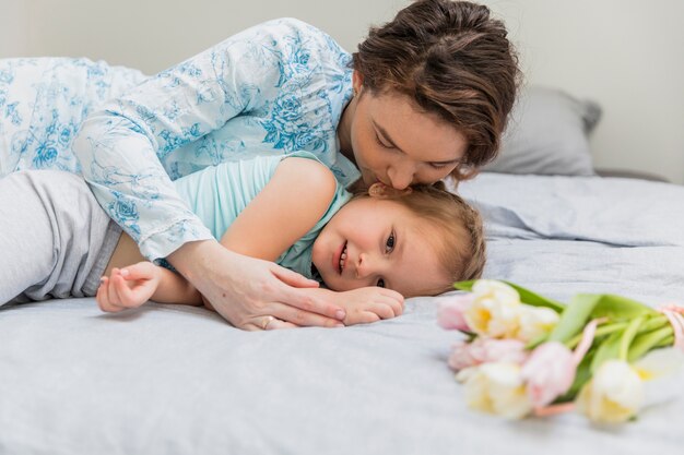 Mother kissing to her innocent daughter on bed