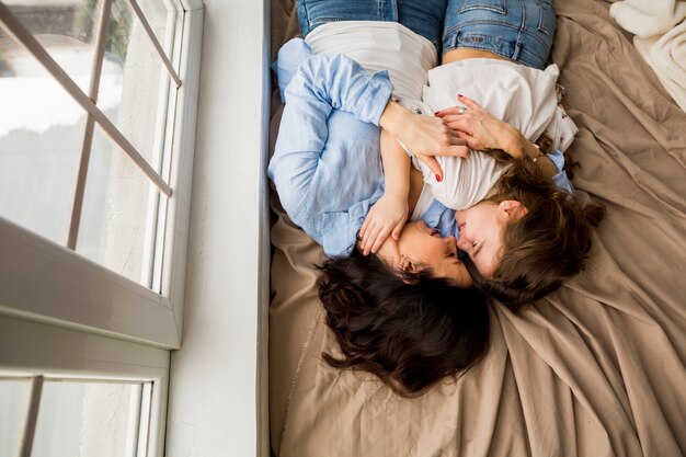 Mother and little daughter hugging on bed