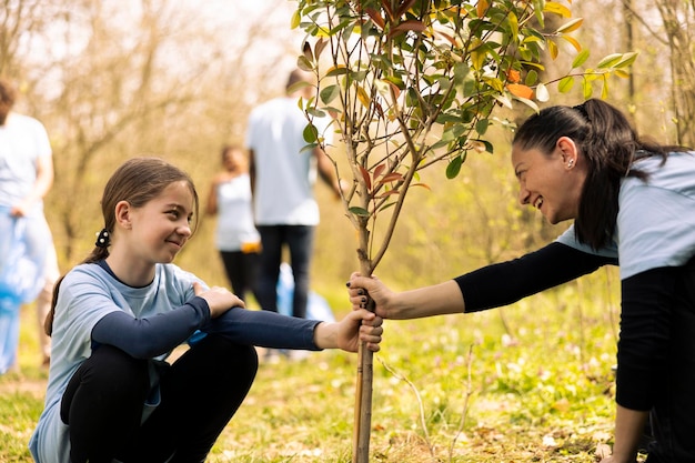 Free photo mother and little girl working together on planting new trees