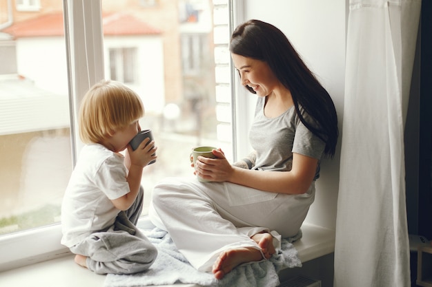 Mother and little son sitting on a windowsill with a tea