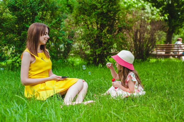 Mother looking at her little daughter making soap bubbles