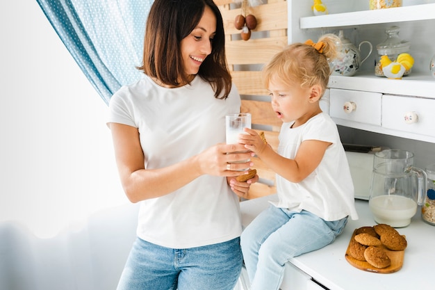 Mother offering a glass of milk to her daughter