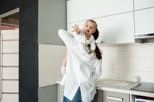 Mother playing with little baby in the kitchen