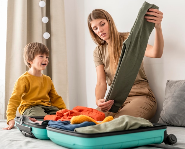 Mother preparing traveling luggage with son