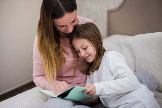 Mother reading together with daughter