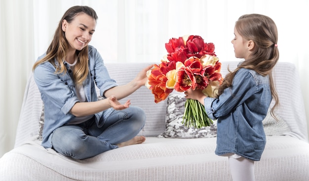 Free photo mother's day. little daughter with flowers congratulates her mother