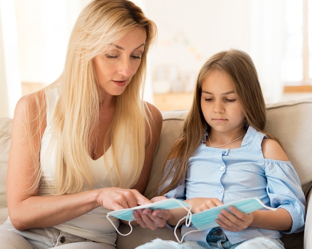 Mother showing daughter how to wear medical masks