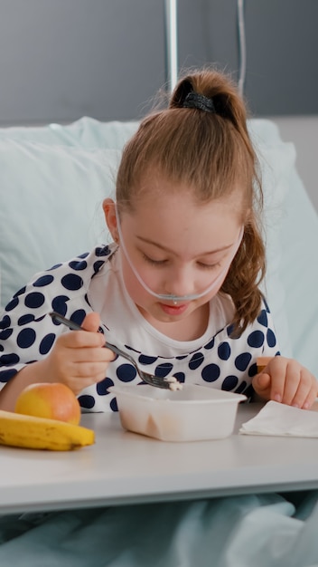 Mother sitting beside sick daughter while eating meal lunch recovering after medical surgery