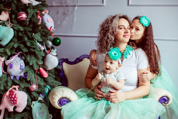 "Mother sitting with daughters smiling hugging"