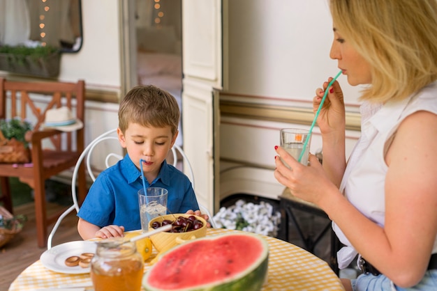 Free photo mother and son drinking lemonade outside