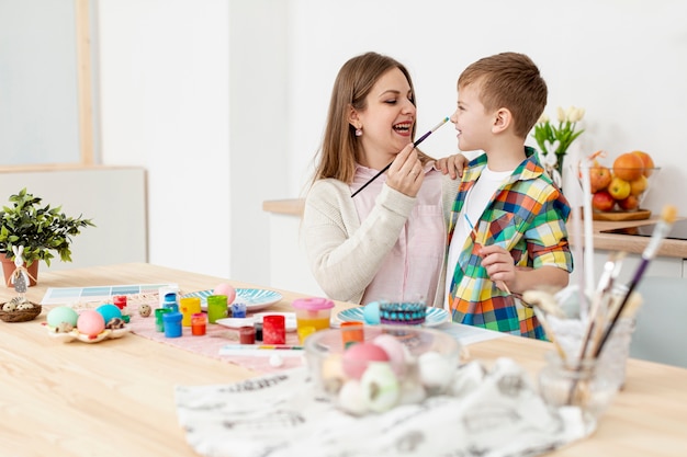 Free photo mother and son having fun while painting eggs