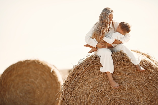 Mother and son. Hay stack or bale on yellow wheat field in summer. Children having fun together.