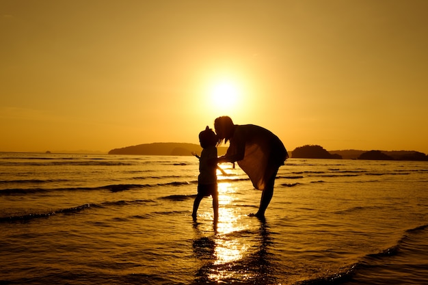 Free photo a mother and son in outdoors at sunset with copy space