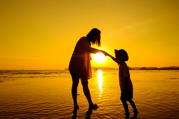 Free photo a mother and son in outdoors at sunset with copy space