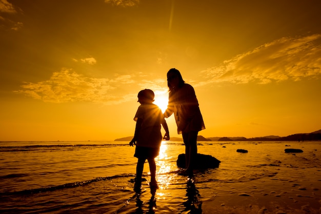 Free photo a mother and son in outdoors at sunset with copy space