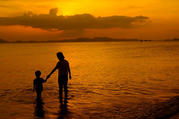 Free Photo a mother and son in outdoors at sunset with copy space