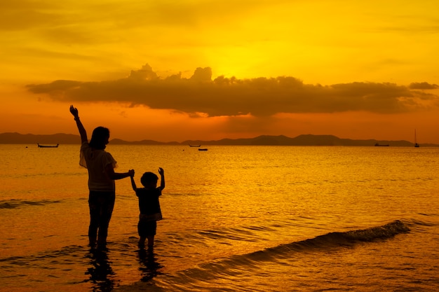 Free photo a mother and son in outdoors at sunset with copy space