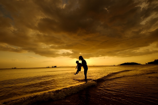 Free photo a mother and son in outdoors at sunset with copy space