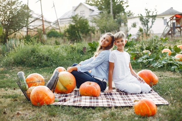 Mother and son  sitting on a garden near many pumpkins