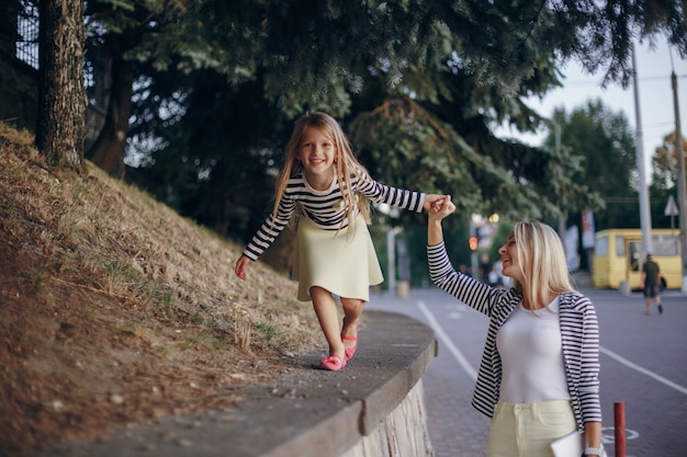 Free Photo mother walking holding her daughter's hand and climbing a wall