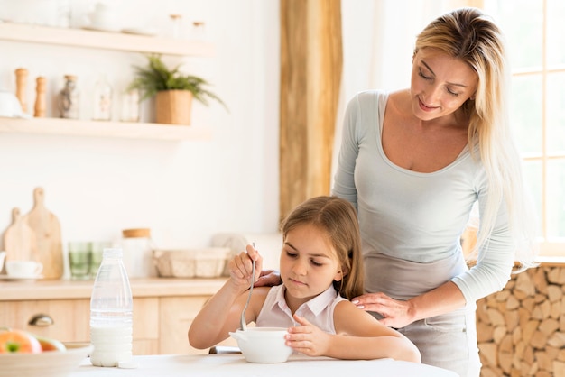 Free photo mother watching her daughter eat breakfast