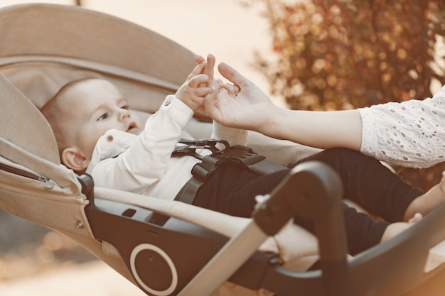 Free photo mother wearing face mask. woman sitting on a bench. mom with baby pram during pandemic taking a walk outdoors.