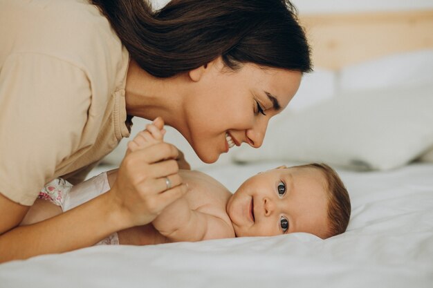 Mother with baby daughter lying on bed