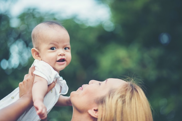 Free photo mother with baby, laughing and playing in the park