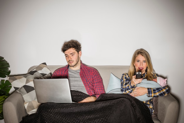 Free photo mother with baby watching tv while father using laptop