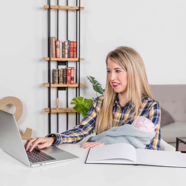 Free photo mother with baby working with laptop at home