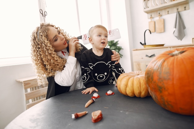 Free photo mother with child in costumes and makeup. family prepare to celebration of halloween.