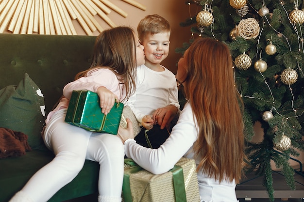 Mother with cute children near christmas tree