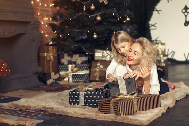 Free photo mother with cute daughter at home near christmas tree