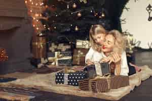 Free photo mother with cute daughter at home near christmas tree