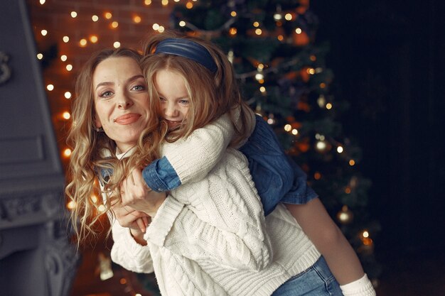 Mother with cute daughter at home near fireplace