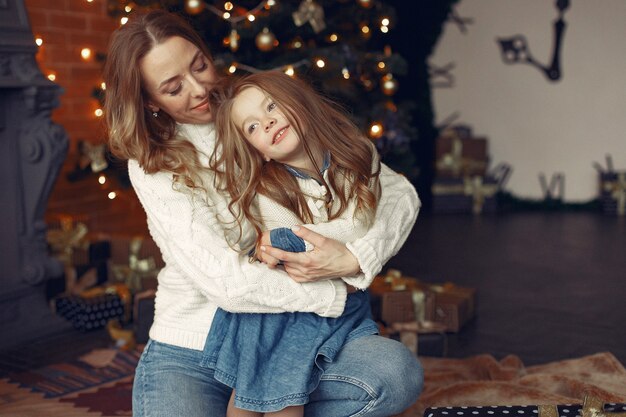 Mother with cute daughter at home near fireplace