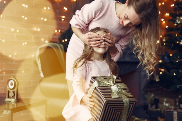 Free photo mother with cute daughter at home near fireplace