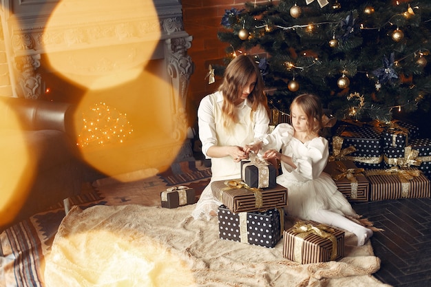 Free photo mother with cute daughter at home near fireplace